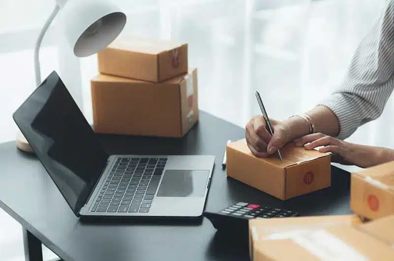A small business owner preparing to ship a package stands in front of an e-commerce store developed by the Tampa Bay Website Design expert team, highlighting the seamless online shopping experience and increased customer satisfaction achieved through professional web development services.